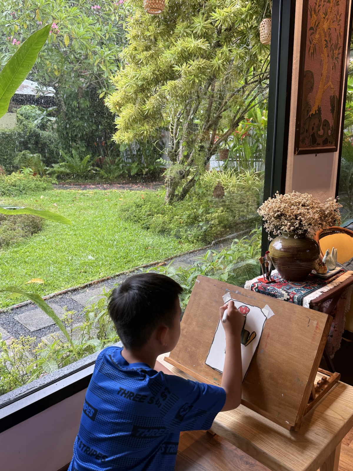 A child drawing at an easel beside the garden window